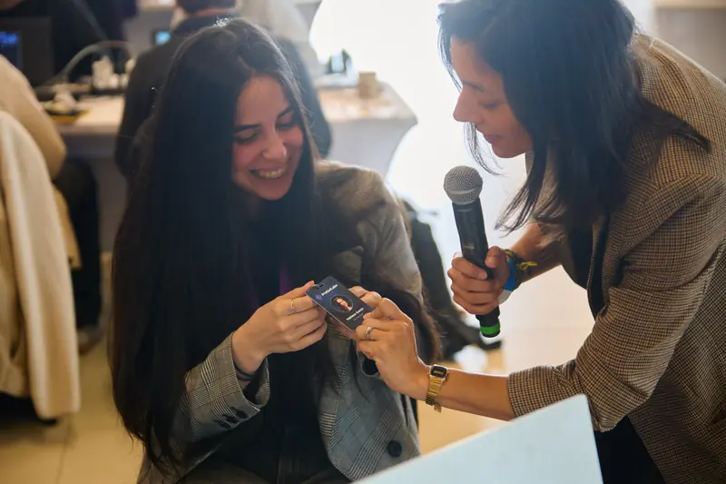 Fabiana García muestra su credencial de ProGarLabs mientras conversa con María José Urrutia, que sostiene un micrófono.