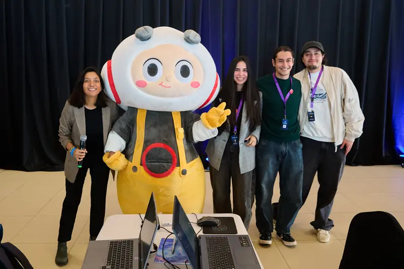 El equipo ProGarLabs posa junto a la mascota del evento y una persona con micrófono.