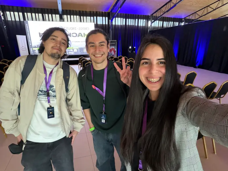 Selfi de tres integrantes del equipo con credenciales del evento en el salón de Empormontt.