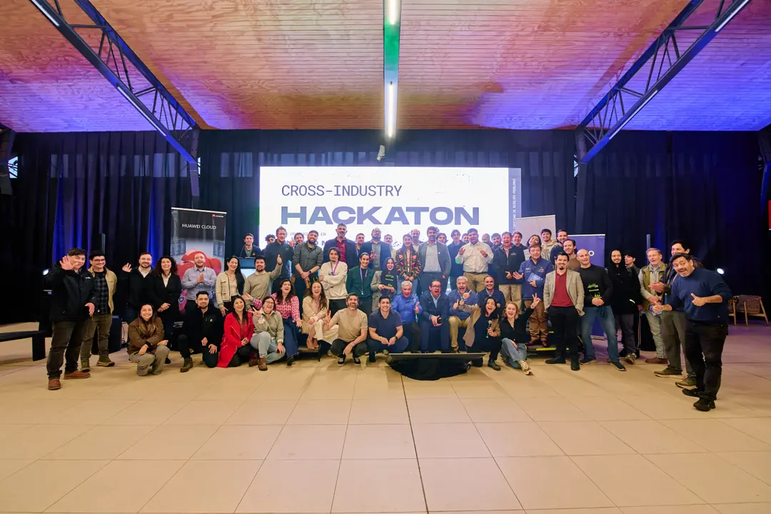 Fotografía grupal de participantes y organización bajo la pantalla de la Cross-Industry Hackaton, en Empormontt.