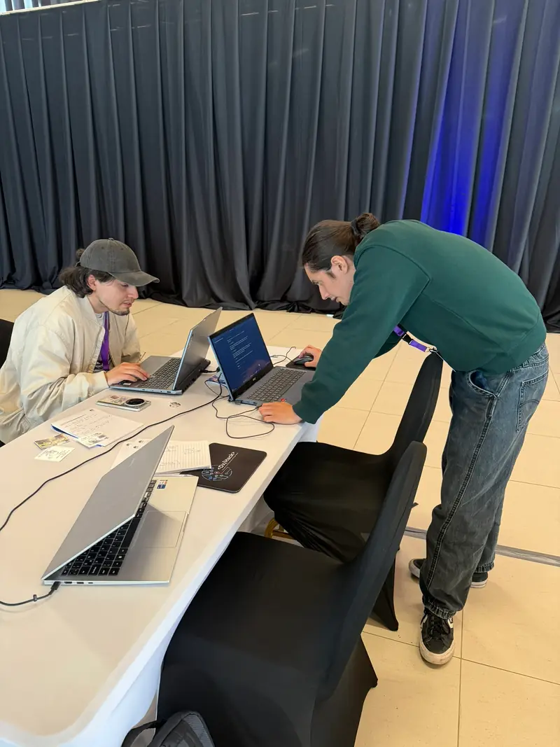 Dos integrantes del equipo revisan los computadores en la mesa de trabajo.